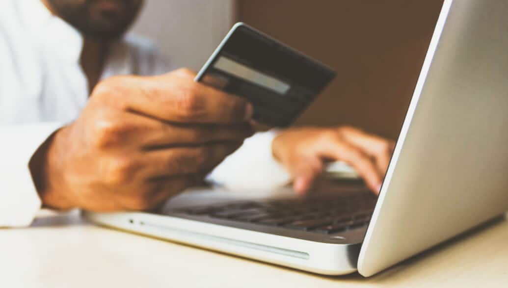 person holding a credit card in front of a laptop