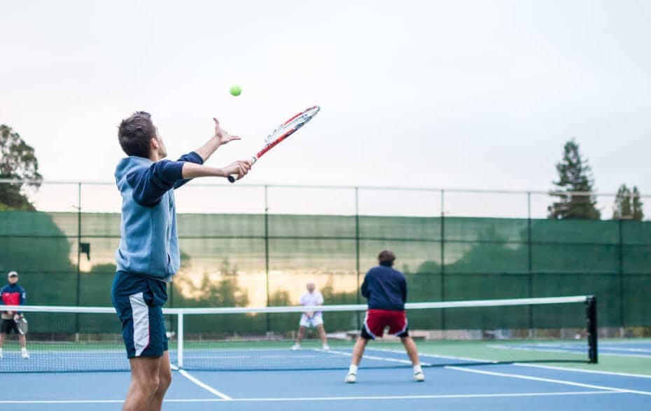 4 men playing doubles on a tennis court.