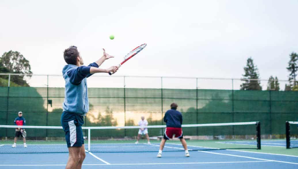 4 men playing doubles on a tennis court.