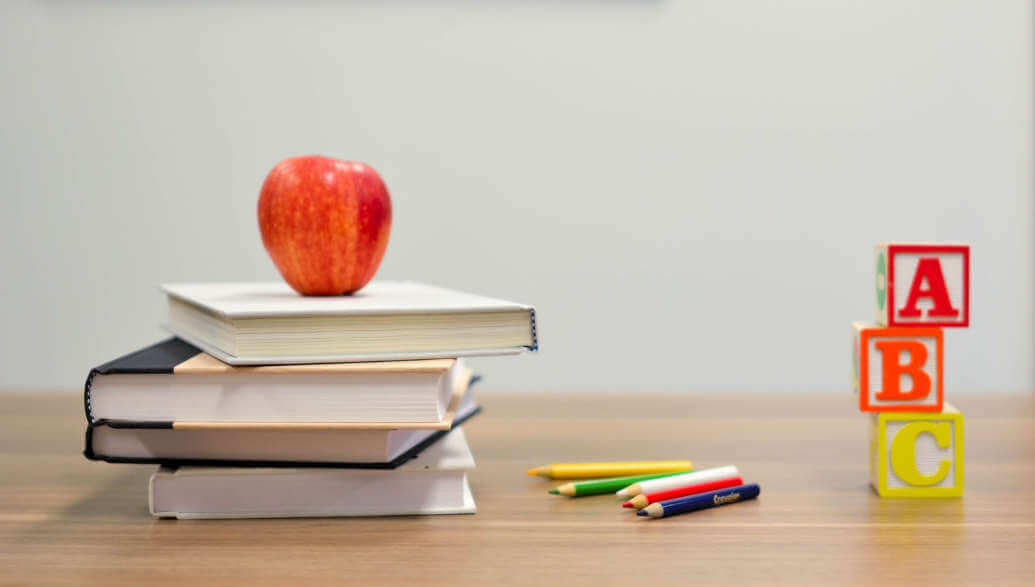 Books and pencils are lying on a desk