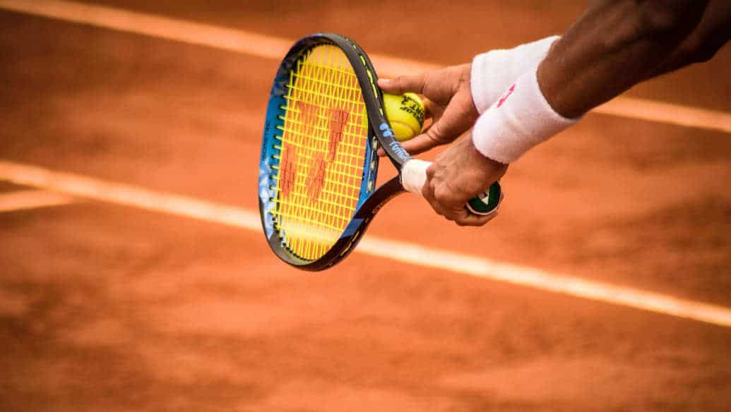 Tennisspieler schlägt mit der linken Hand auf dem Sandplatz auf