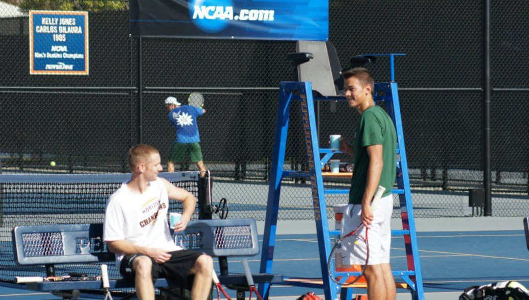 Two people taking a water break on a tennis court