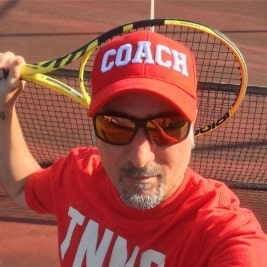 Tennistrainer Koray hält einen Tennisschläger in seiner rechten Hand.