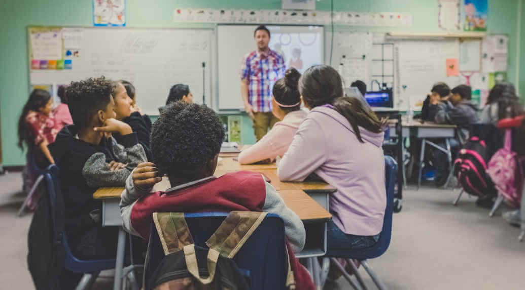 Ein Lehrer unterrichtet eine Klasse voller Grundschüler.