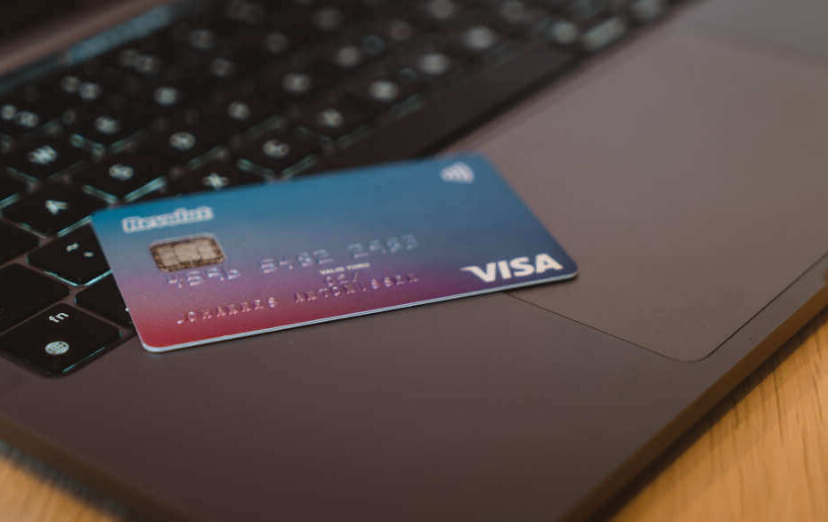 Eine VISA-Kreditkarte liegt auf einem silbernen Laptop.