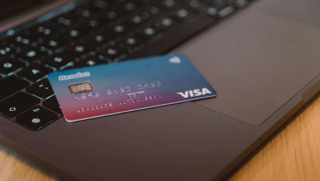 Eine VISA-Kreditkarte liegt auf einem silbernen Laptop.