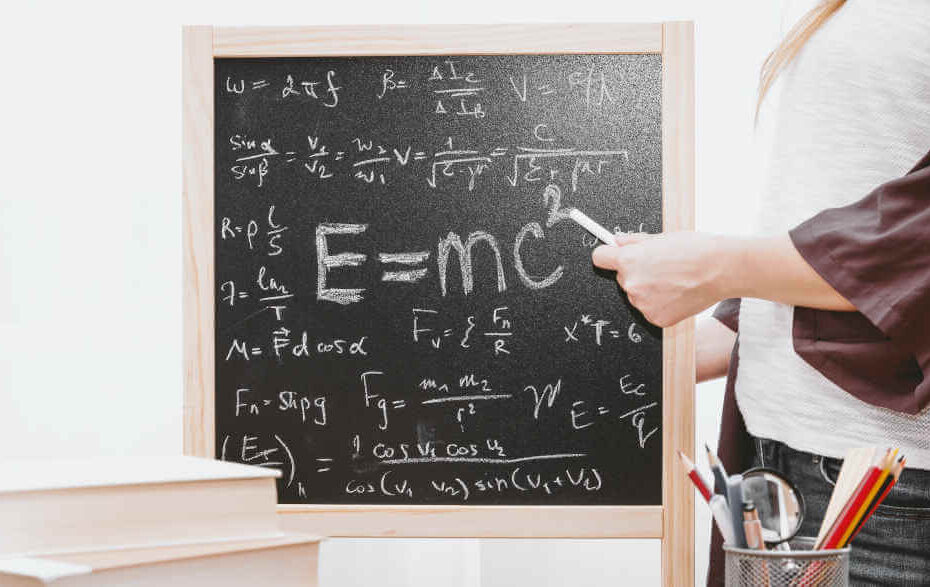 Ein Mann zeigt auf mathematische Gleichungen, die auf einer Tafel stehen.