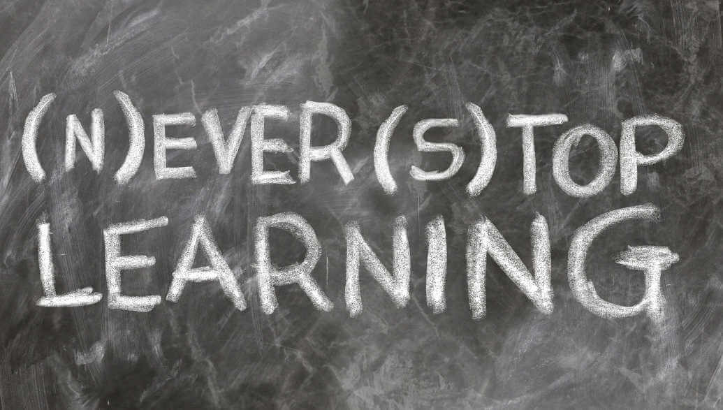 The sentence "(N)ever (S)top Learning" is displayed on a board.